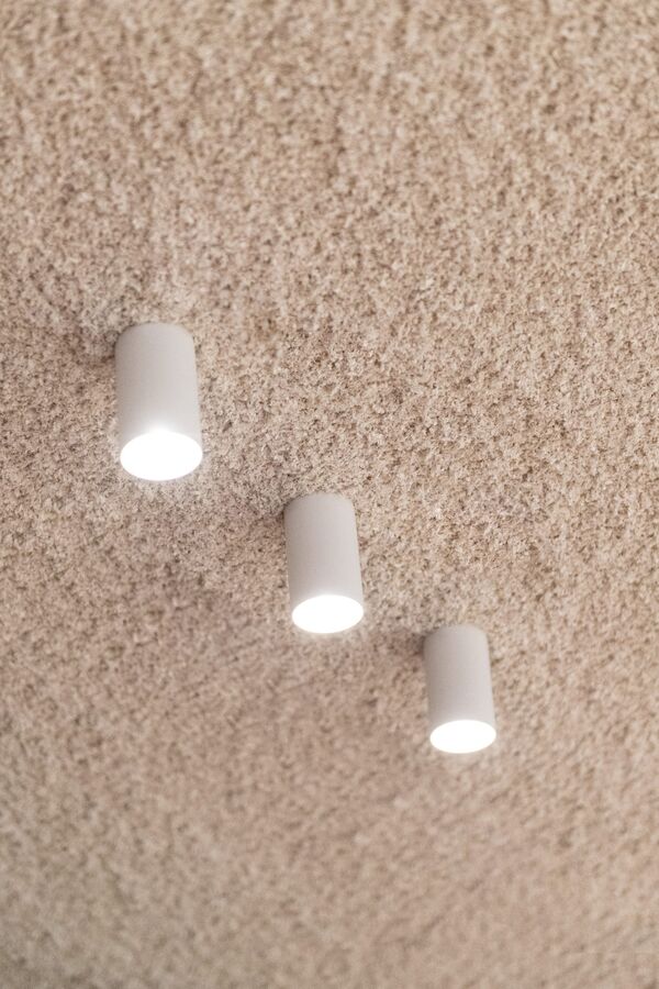 Drie witte opbouwspots tegen een beige gespoten plafond