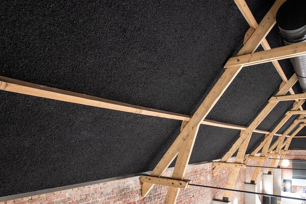 Zwart gespoten plafond tussen zichtbare houten spanten