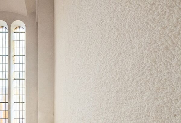 Hoek van een wand afgewerkt in lichtbeige spuitpleister