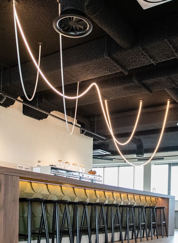 Zwart gespoten plafond met zichtbare leidingen boven een bar