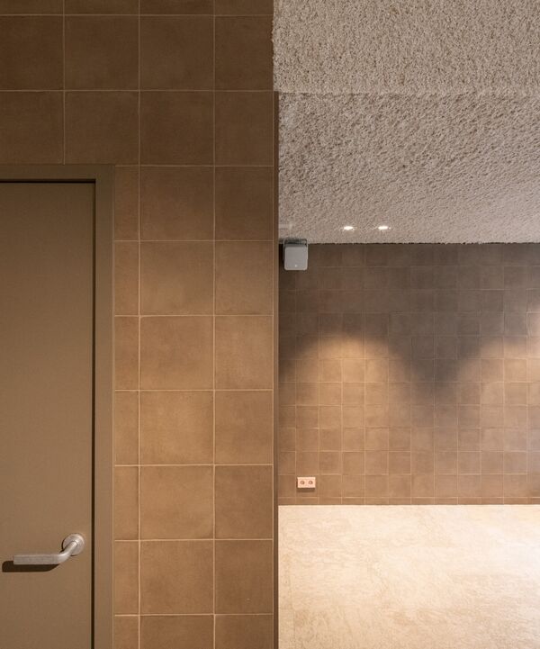 Gang met beige tegelwand en een gespoten plafond