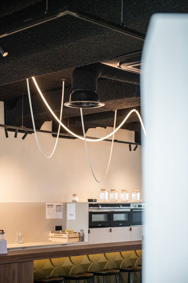 Kantine met keuken onder een zwart Zenko-plafond met hangende lichtsnoeren